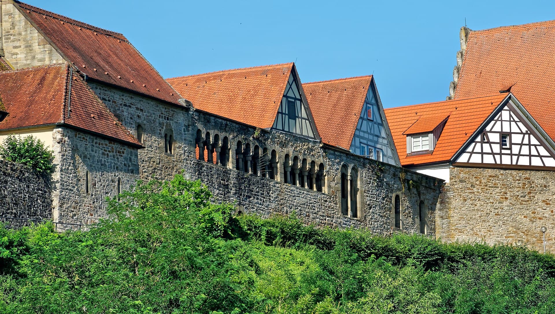 Die Nordwand des staufischen Palas in Bad Wimpfen mit ihrer Reihe romanischer Arkadenbögen, links die Pfalzkapelle, am rechten Bildrand der Staffelgiebel des Steinhauses.