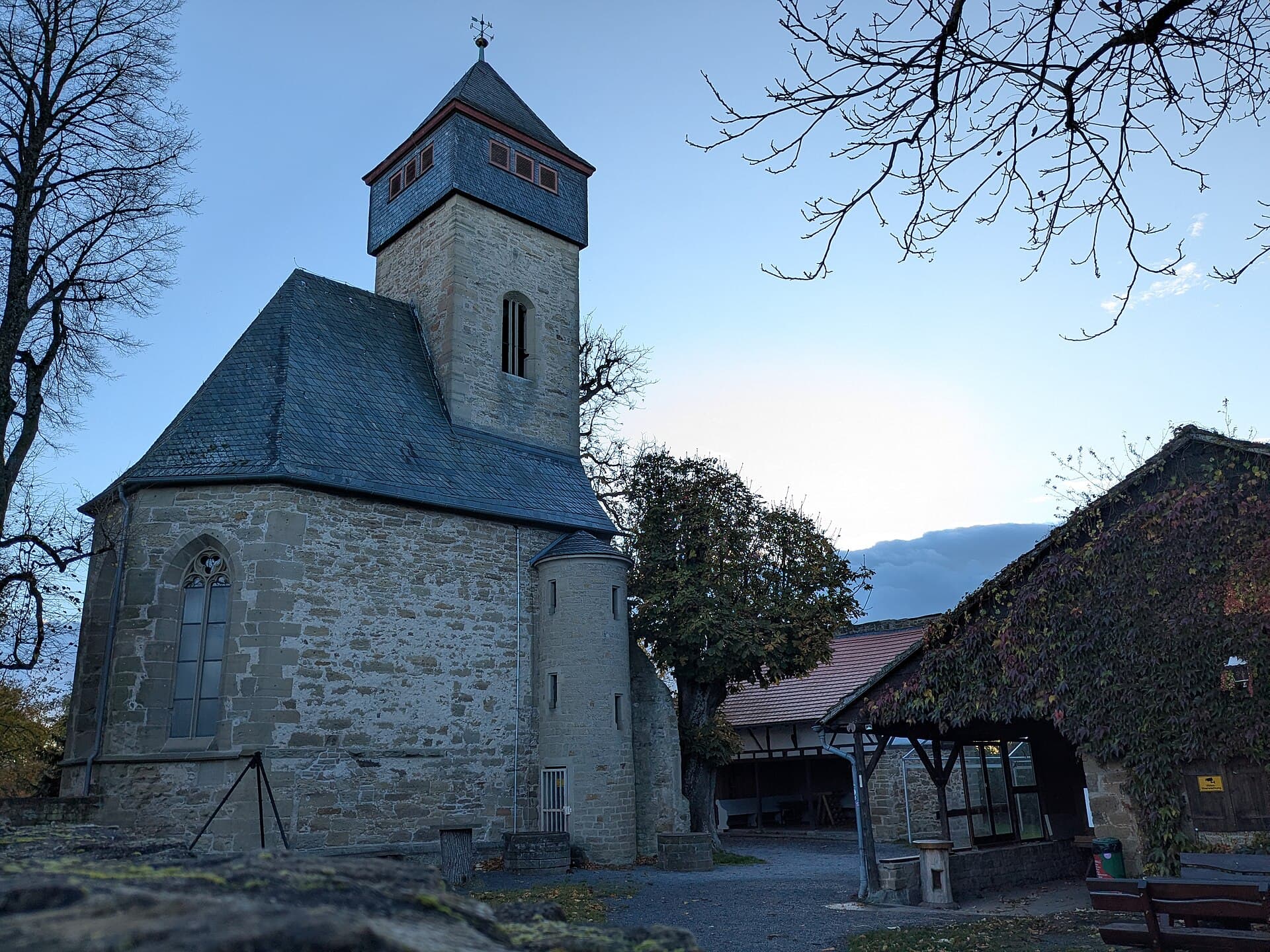 Die Ottilienkapelle auf dem Ottilienberg von Nordosten: gotischer Chor aus Sandstein, dahinter der Turm mit schiefergedecktem Aufsatz und angebautem runden Treppenturm, rechts ein efeubewachsenes Nebengebäude.