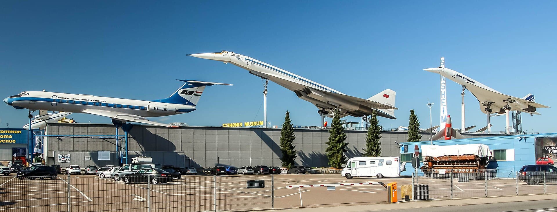 Tupolew Tu-134, Tu-144 und Concorde über den Hallen des Technik Museums Sinsheim, davor der umzäunte Museumsparkplatz