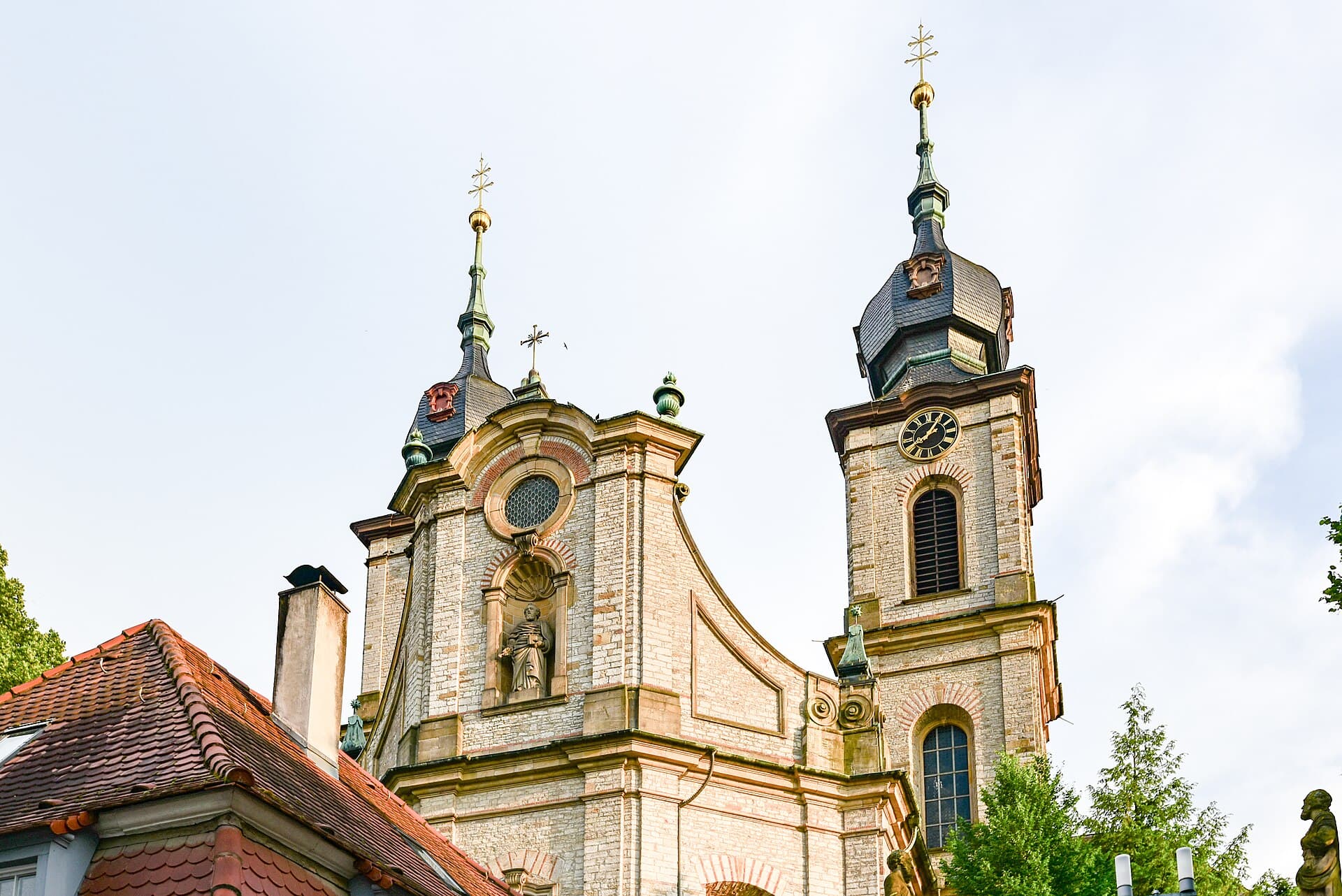 Fassade und Türme der Barockkirche St. Peter in Bruchsal von unten, mit der Heiligenfigur in der Giebelnische und dem Uhrturm