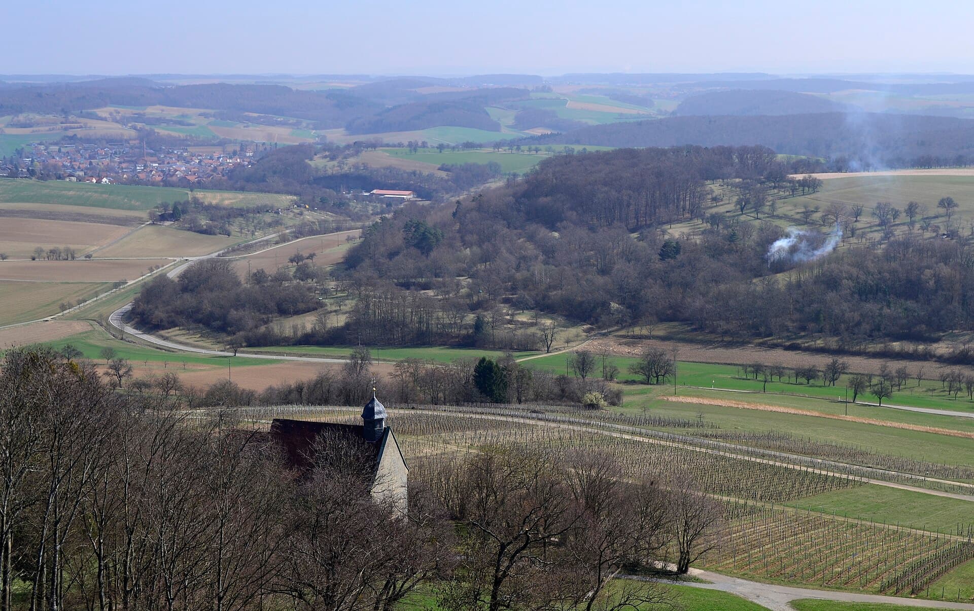 Blick von der Burg Steinsberg nach Osten über die Wallfahrtskirche St. Anna und Rebzeilen am Burgberg auf Wälder, Obstwiesen, Felder und ein Dorf im Hügelland